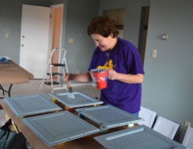 A volunteer paints cabinet doors at the ACRES house. ACRES works with adults on the Autism Spectrum to transition to independent living and learn vocational skills.